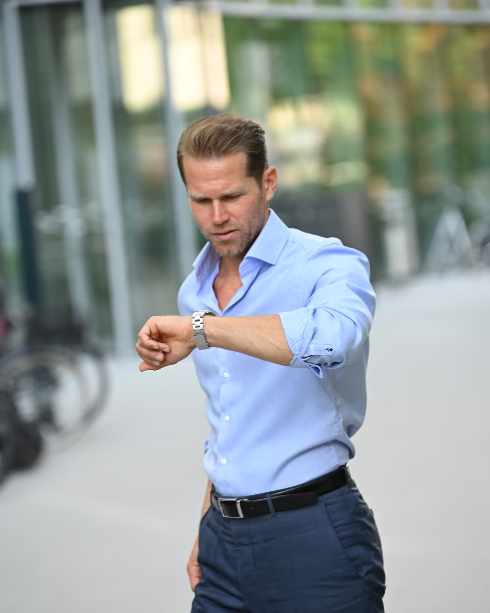 Norman Bartsch im hellblauen Hemd, der auf die Uhr schaut.