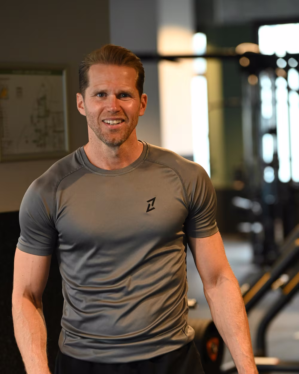 Norman im grauen Trainingsshirt im Fitnessstudio, lächelnd.