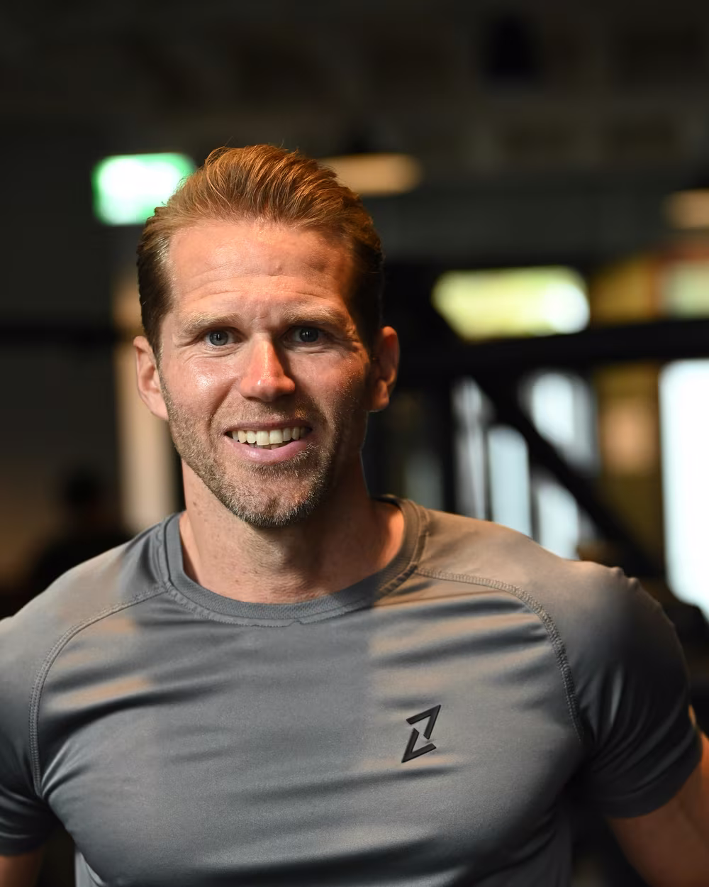 Norman im grauen Trainingsshirt im Fitnessstudio, lächelnd.
